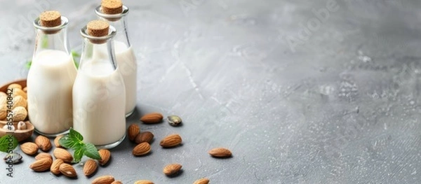 Obraz Vegan alternative nut milk in glass bottles on a gray background. Healthy vegan food concept. Copy space image. Place for adding text or design