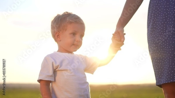 Fototapeta people in the park. mother and son walk at sunset in nature in the summer in the park. happy family a kid dream concept. mother lifestyle and son holding hands in nature. happy family together