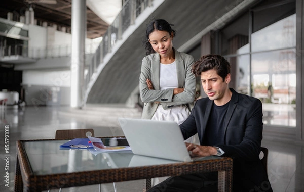 Fototapeta Latino man and African American businessperson brainstorming startup small business strategy together. Young multiracial businesswoman and colleague serious working on planning. Diversity people team.