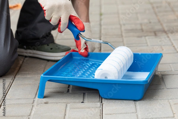 Fototapeta Construction work, plastering and wall priming. Builder's hand with paint roller.