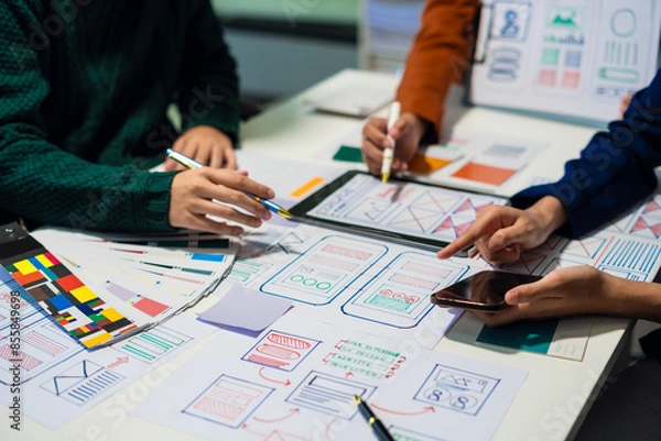 Fototapeta UX developer and ui designer brainstorming about mobile app interface wireframe design with customer breif and color code at office.