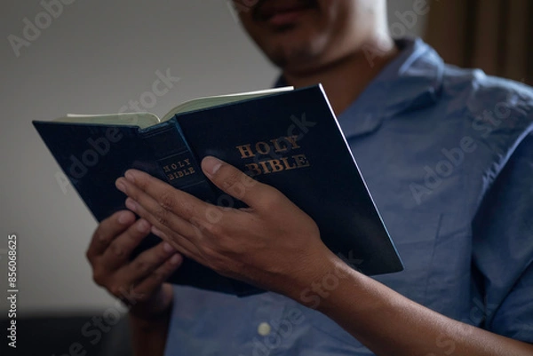 Fototapeta Closeup of man is reading a book or Bible in little light.