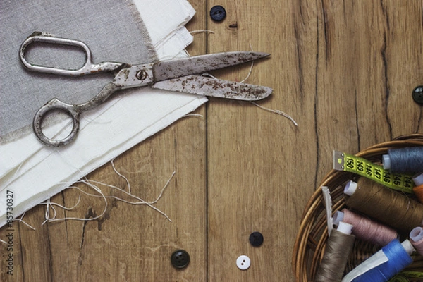 Obraz Sewing kit. Scissors, bobbins with thread and needles on the old wooden background