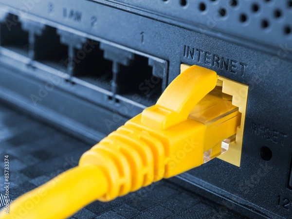 Fototapeta Yellow network cable connected to a router or modem