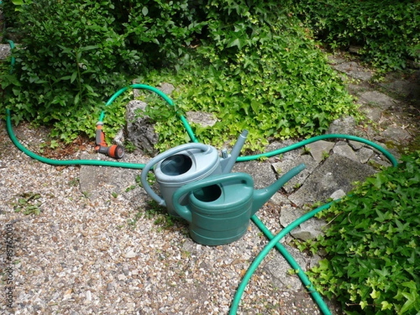 Fototapeta garden watering cans and watering hose, in a garden