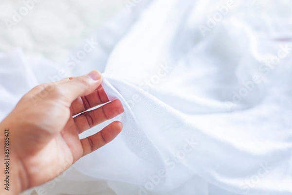 Fototapeta Hand touching cloth. Natural fabric, soft to the touch. Hand holding a white cloth to select. Good fabric.