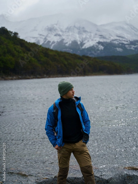 Obraz Photo of a handsome young man in profile, wearing a green woolly hat and blue jacket, posing in front of the Beagle Channel in Tierra del Fuego National Park, Argentina.