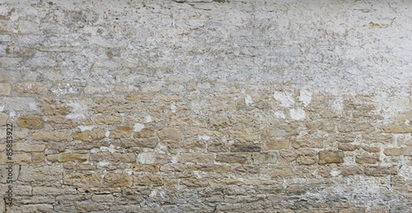 Fototapeta Background of old vintage  limestone wall with peeling plaster