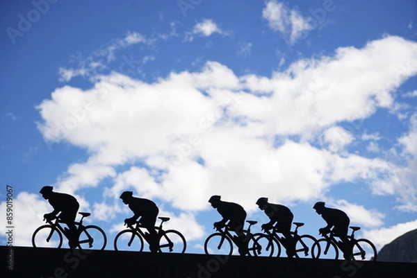 Fototapeta Lanslebourg-Mont-Cenis , France - June 20 2024: A group of cyclists tackle the steep Alpine climb in the back light.