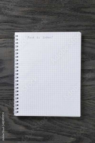 Fototapeta back to school phrase in notepad with chequered pages on gray