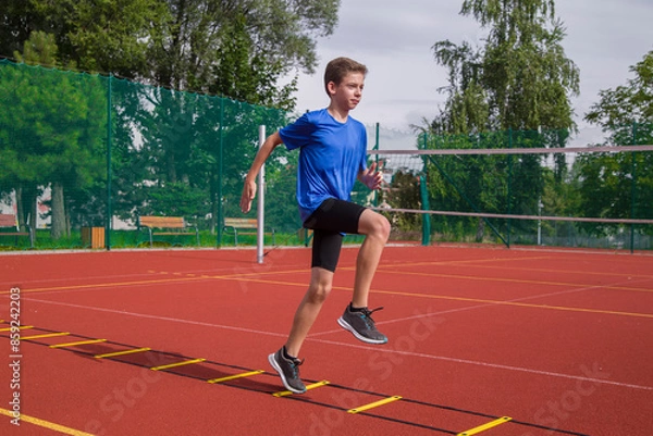 Obraz An athlete does special running exercises on a ladder.