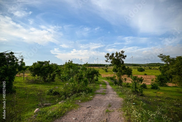 Obraz road in the countryside with wind farm in the background, Clean and smart energy exploitation, contributing to local economic development