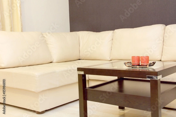 Fototapeta Interior with coffee table and white corner leather sofa .