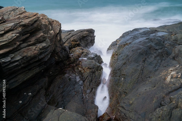 Fototapeta The waves crash against the rocks on the shore