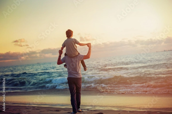 Fototapeta Happy father and son having great time on the beach in sunset