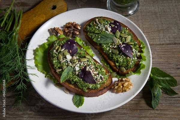 Obraz Toasts with homemade pesto sauce with sunflower seeds, sesame seeds and basil leaves on a light plate