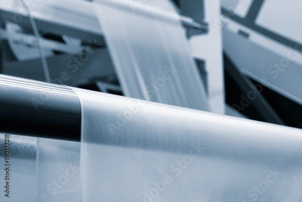 Fototapeta Automatic polyethylene plastic bag production machine with lighting effect. Close-up of the roller of the plastic bag production machine in the light blue scene. product packaging concept