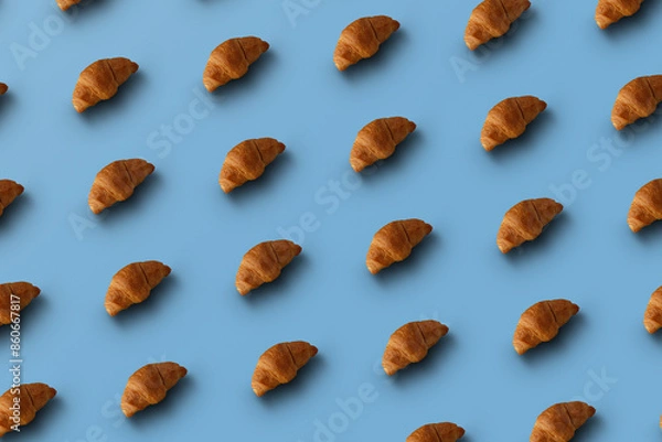 Fototapeta Pattern of baked croissants with a blue background. Delicious pastries