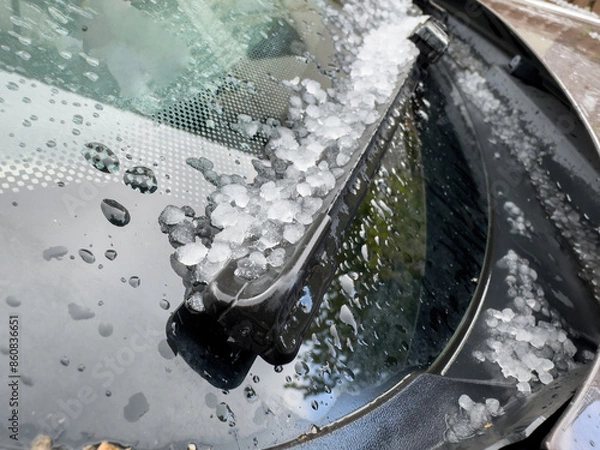 Fototapeta Close-up of a car windshield covered in hailstones and raindrops, highlighting the aftermath of a hailstorm with ice pellets accumulated around the windshield wiper
