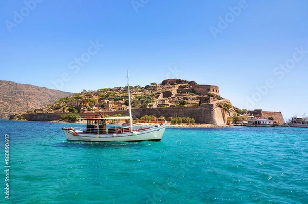 Fototapeta A white touristic boat in turquoise water of the Gulf of Elounda in front of Spinalonga island, north-eastern Crete, in the municipality of Agios Nikolaos