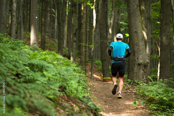 Obraz single man with cap running cross country race on the forest trail