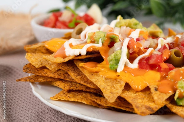 Fototapeta Crispy tortilla chips topped with melted cheddar cheese and salsa	