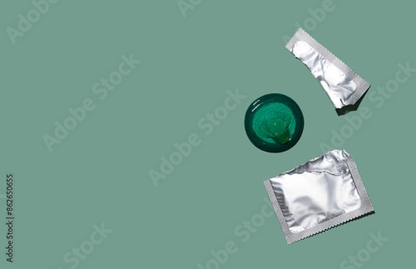 Fototapeta Condom out of package on a mint green background. A condom use to reduce the probability of pregnancy or sexually transmitted disease (STD). Safe sex and reproductive health concept. Top view.
