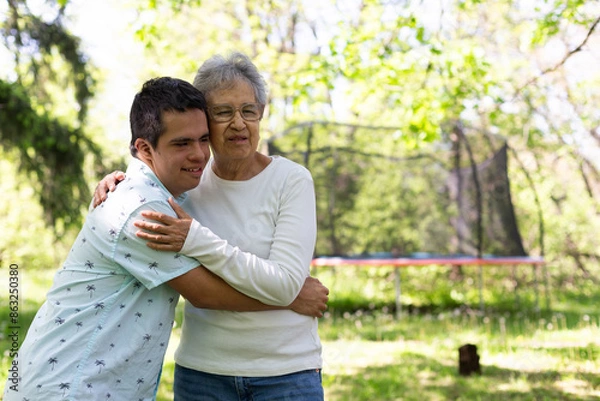 Obraz A man and an old woman embrace in a park. The man is wearing a blue shirt . The scene is peaceful and touching.