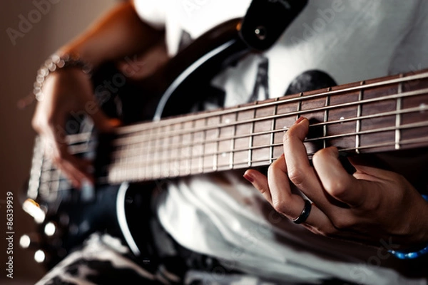 Fototapeta Young adult girl playing five string bass guitar. Color image in horizontal orientation