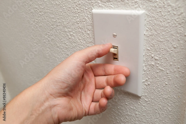 Fototapeta Hand turning wall light switch off. color image in horizontal orientation