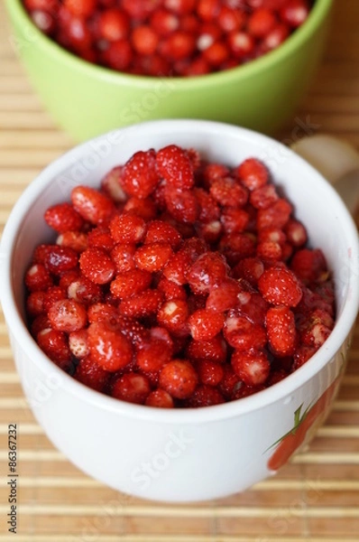 Fototapeta Red fresh wild strawberry in a big white mug stand on a table