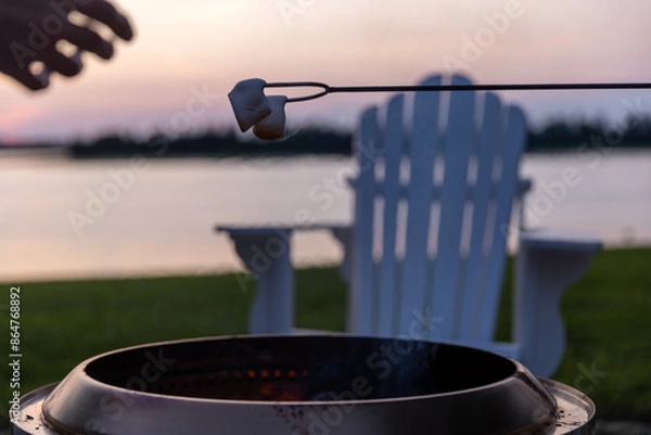 Fototapeta hand reaching for Marshmallows above fire pit 