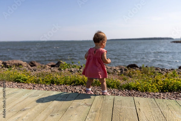 Fototapeta Toddler girl on path in front of ocean 
