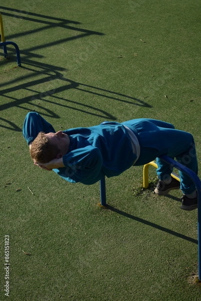 Fototapeta A dedicated young athlete puts in the hard work, vigorously training on gym equipment outdoors to prepare his body. He builds strength and endurance before hitting the field or court for competition