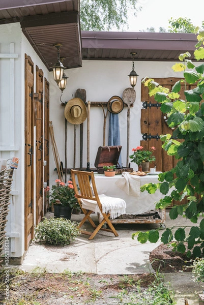 Fototapeta Picturesque courtyard with wooden furniture, gramophone, straw hats and various utensils for working in the garden. Nostalgic motif. A series of lifestyle photographs.