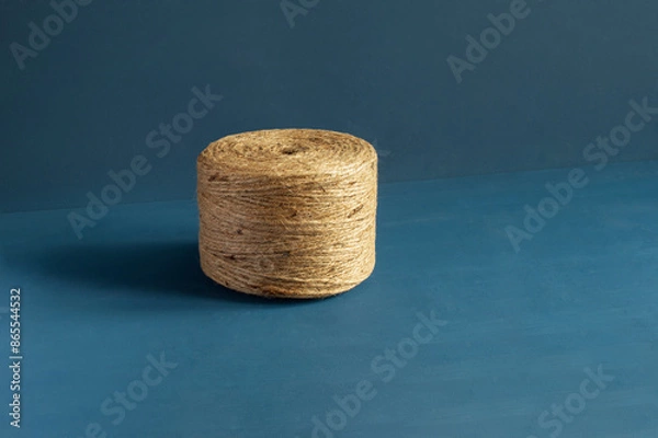 Fototapeta An insolated spool of natural fiber twine  natural color jute twine set against a striking hand-painted blue background with copy space focus on the twine’s texture.  Craftsmanship essence.
