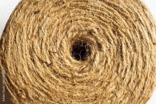 Fototapeta Close-up image of a natural jute twine roll viewed from the top showcasing the central hole, displaying its intricate, fibrous texture captures the detailed pattern and organic quality of the rope.