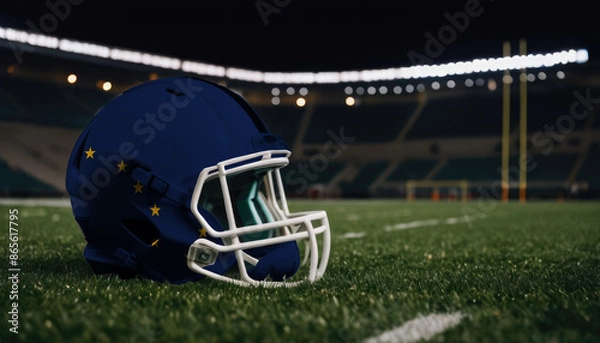 Fototapeta An American football helmet with the Alaska flag design sits on a field at night, under stadium lights
