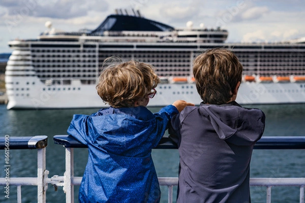 Fototapeta Two boys on a ferry deck departing Copenhagen Harbor. Child with blond curls points something out to his brother, gazing at a cruise ship ashore