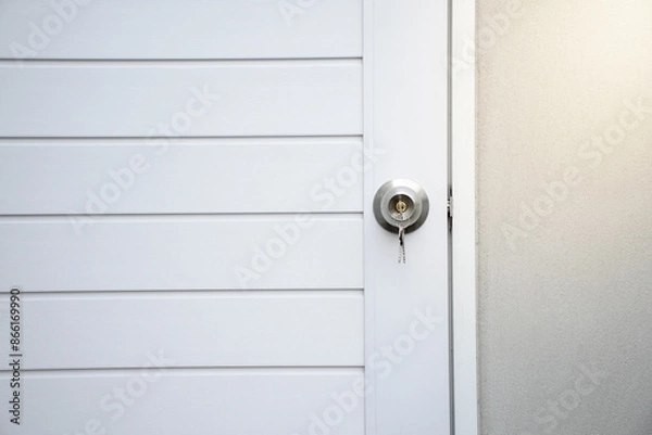 Obraz Silver knobs and keys on white modern wooden doors against the gray concrete background for forgot to close the door or lost the key and safety with security concept.