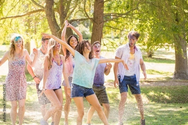 Fototapeta Young friends having fun with hose in the park