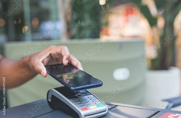 Obraz man paying contactless with mobile phone in restaurant.