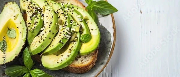 Obraz Delicious avocado toast garnished with seeds and fresh basil on a rustic plate, perfect healthy breakfast or snack idea.