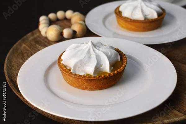 Fototapeta Lemon tart with zingy lemon curd topped with whipped lemon cream on white plate on wooden tray