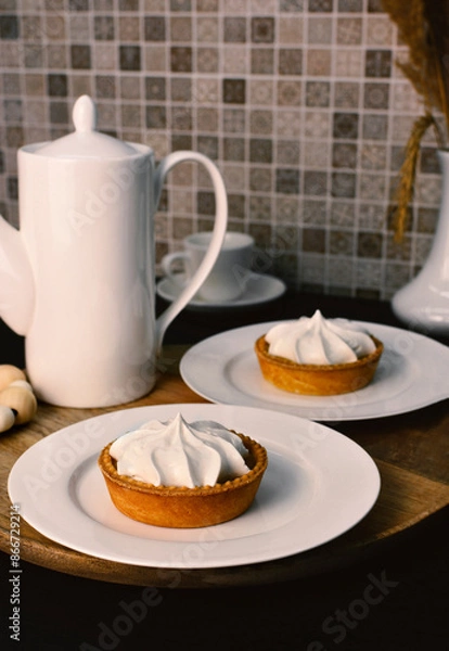 Fototapeta Lemon tart with zingy lemon curd topped with whipped lemon cream on white plate on wooden tray.
