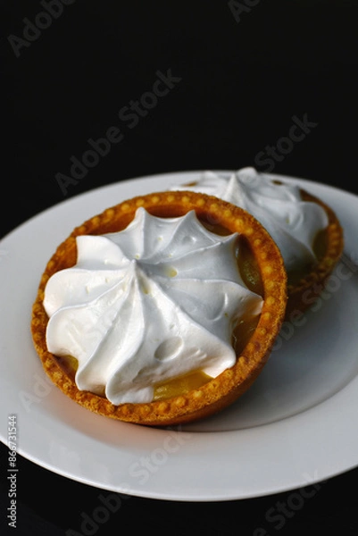 Fototapeta Lemon tart with zingy lemon curd topped with whipped lemon cream on white plate on dark background