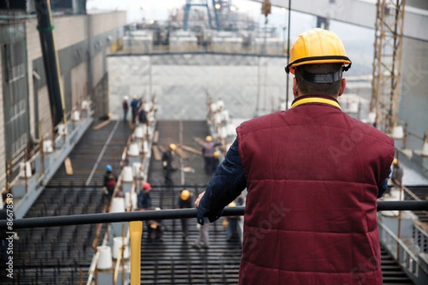 Obraz Engineer supervising workers from platform