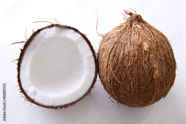 Fototapeta Whole and halved coconuts shot from above on a white backgroundfrom above
