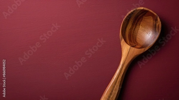 Fototapeta Wooden spoon on dark red background, emphasizing texture and grain