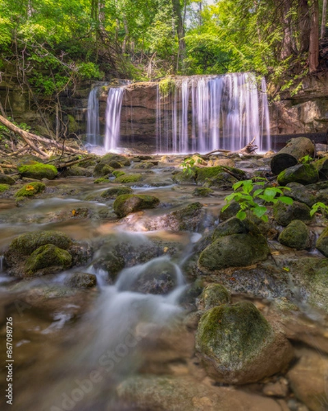 Fototapeta Peaceful waterfall with water cascading down from a lush green landscape. Terra Cotta Conservation Area, Ontario Canada